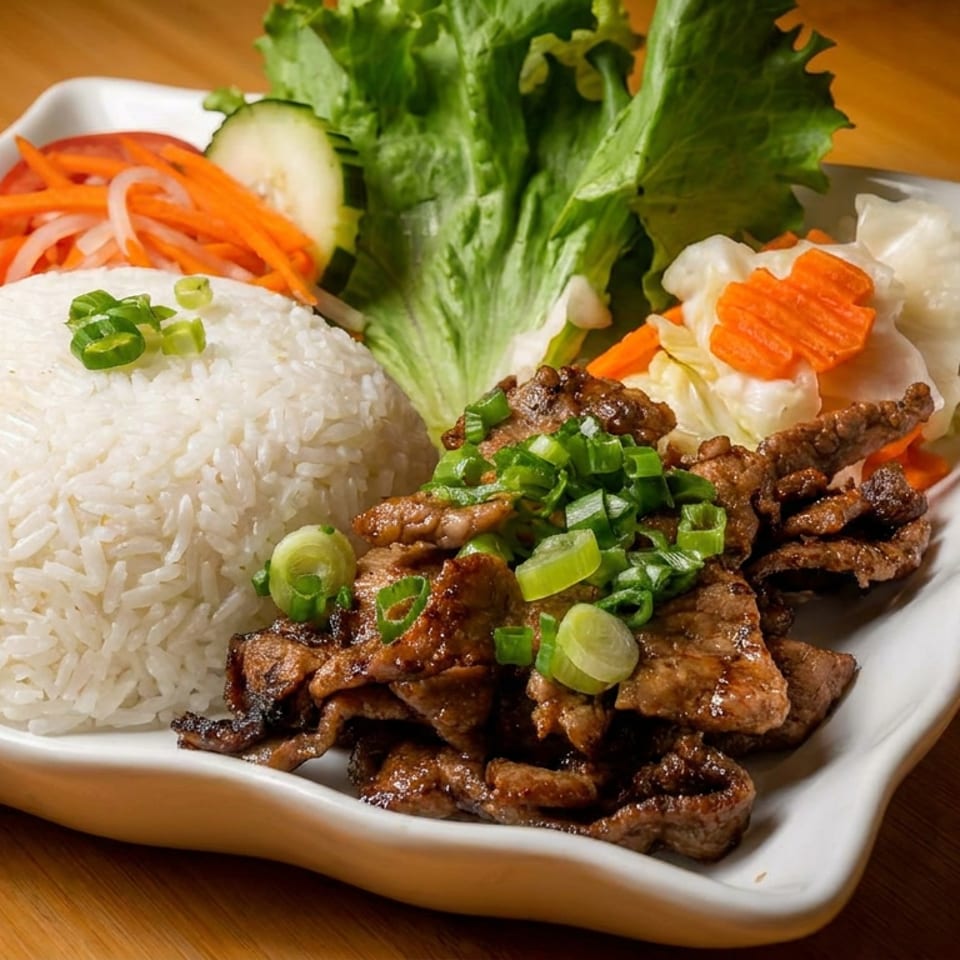 Grilled beef with rice, lettuce, pickled carrots, and cucumbers on a white plate.