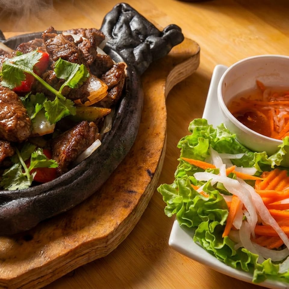 Sizzling beef with onions and cilantro, served with rice, salad, and dipping sauce.